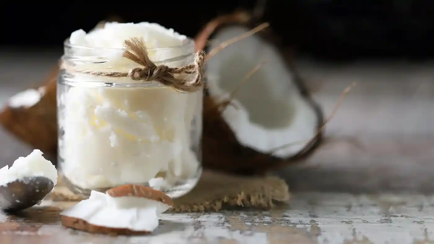 Coconut pieces in glass jar with coconut in the background