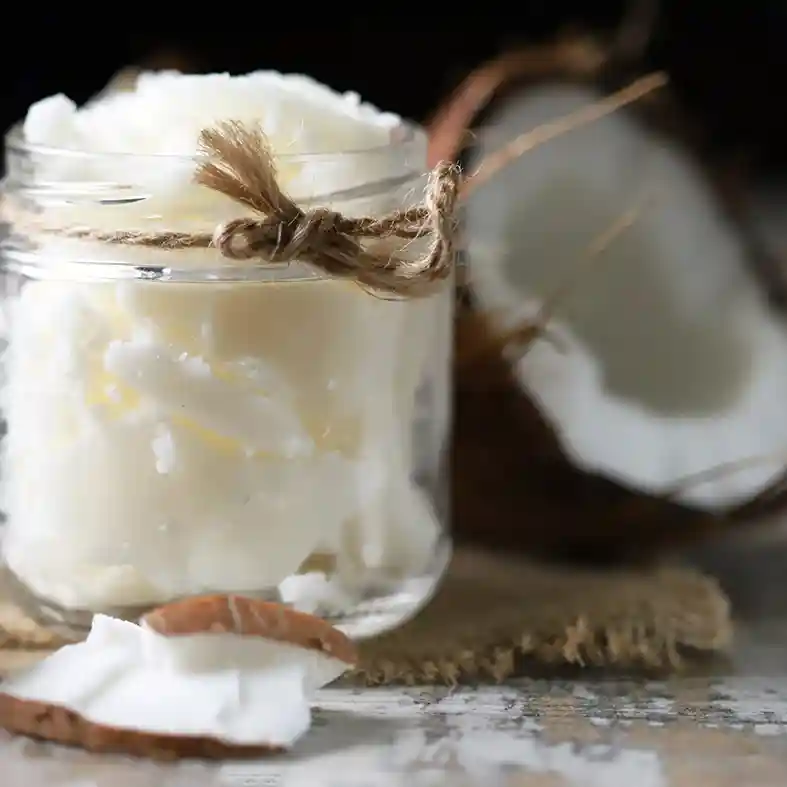 Coconut pieces in a glass jar with coconut n the background