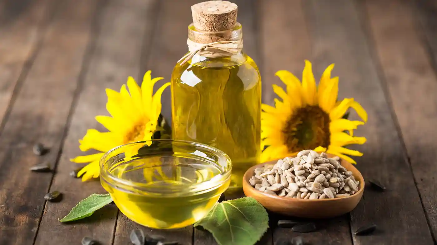 Oil in glass bottle with cork with sunflowers behind it