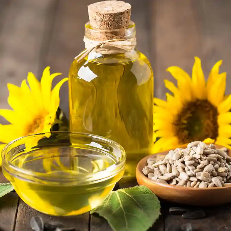 Oil in glass bottle with cork with sunflowers behind it