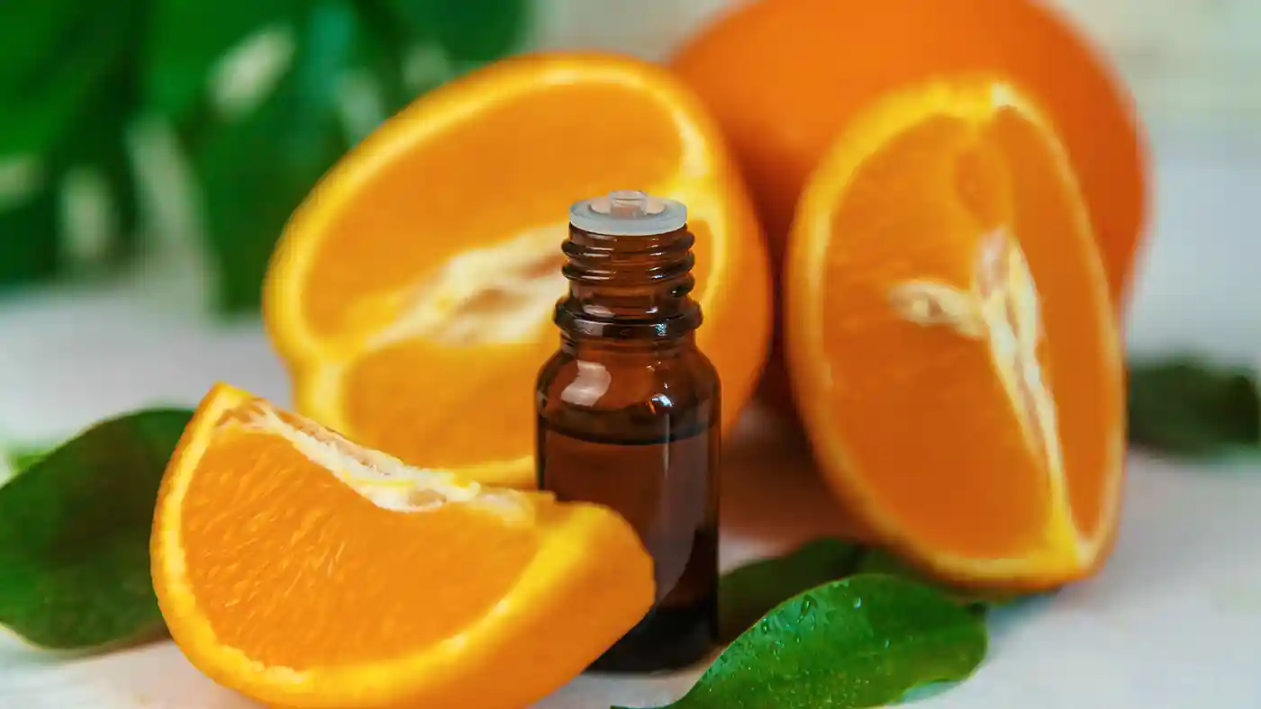 Orange slices around an amber essential oil glass bottle